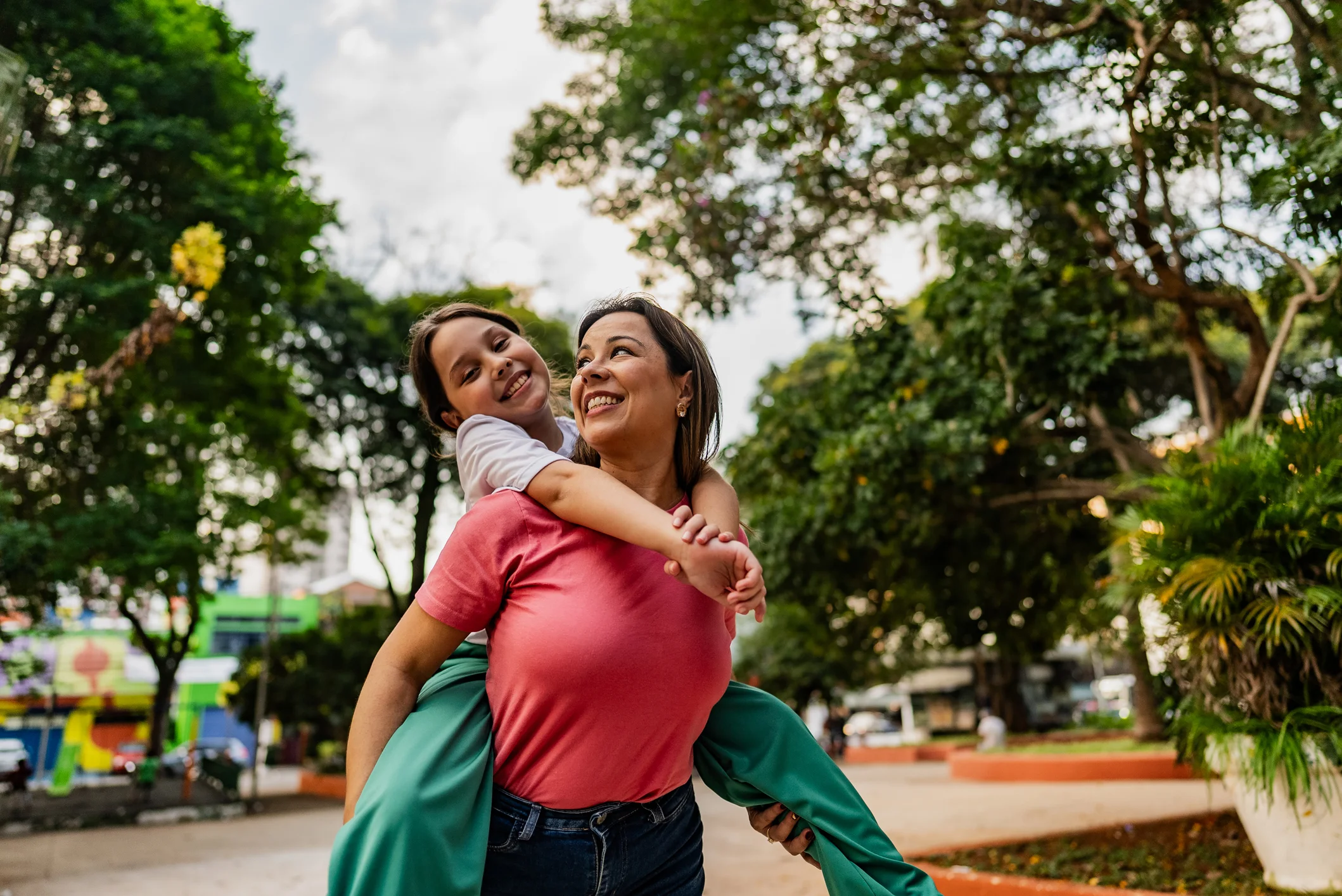 Una madre alzando a su hija disfrutando en el parque